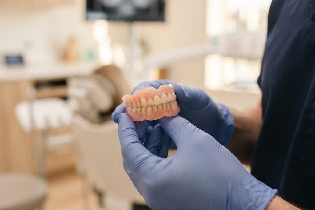 A clinician holding a finished denture in the surgery